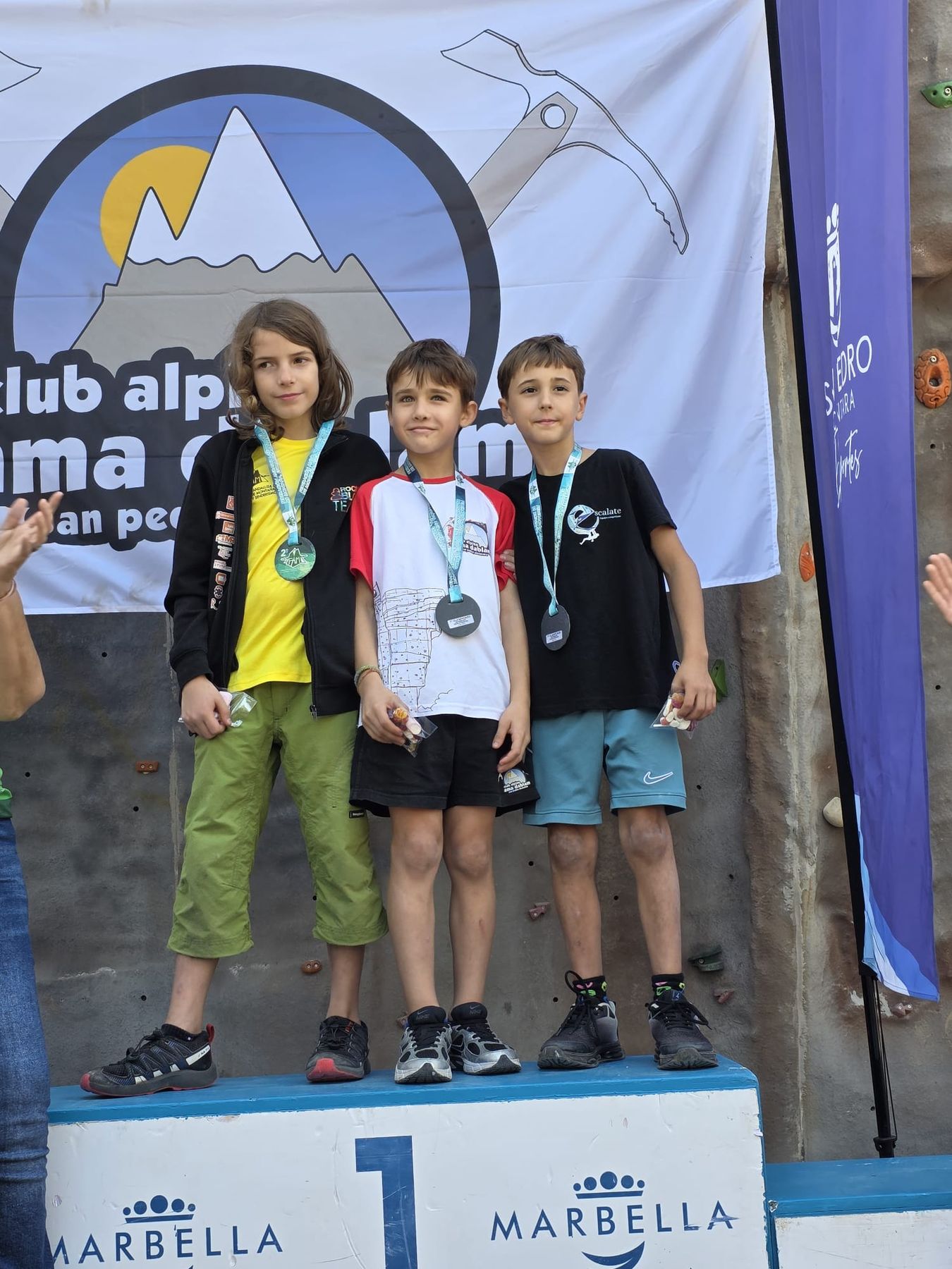 Podio masculino bajo la bandera del club en San Pedro