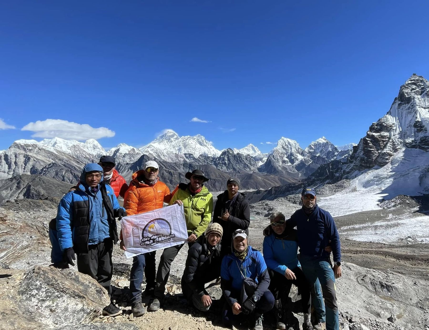 Grupo del club con la bandera en el Himalaya, con el Everest al fondo