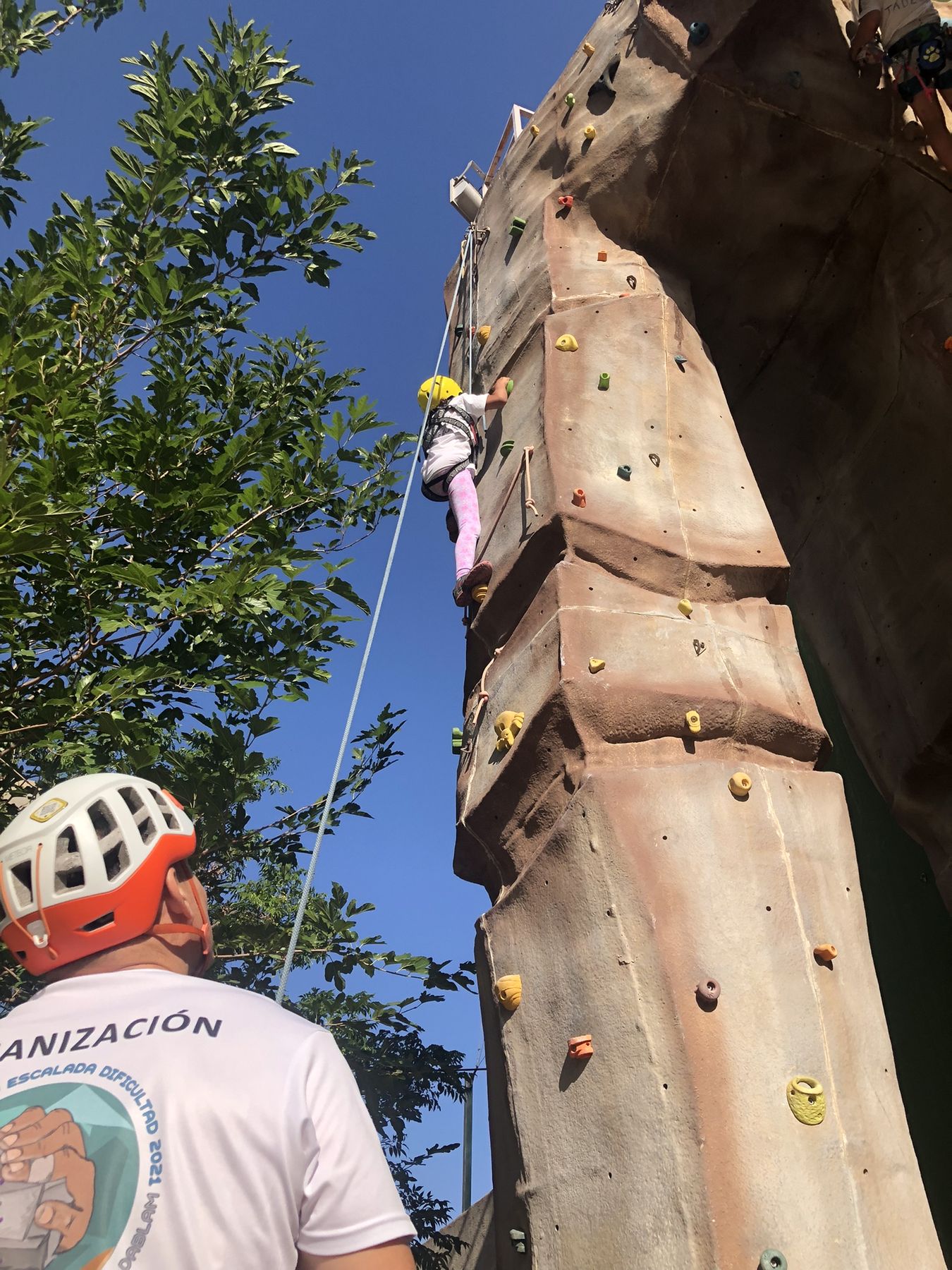 A child climbs El Tornillo while a club instructor belays from below, at the end-of-year open day