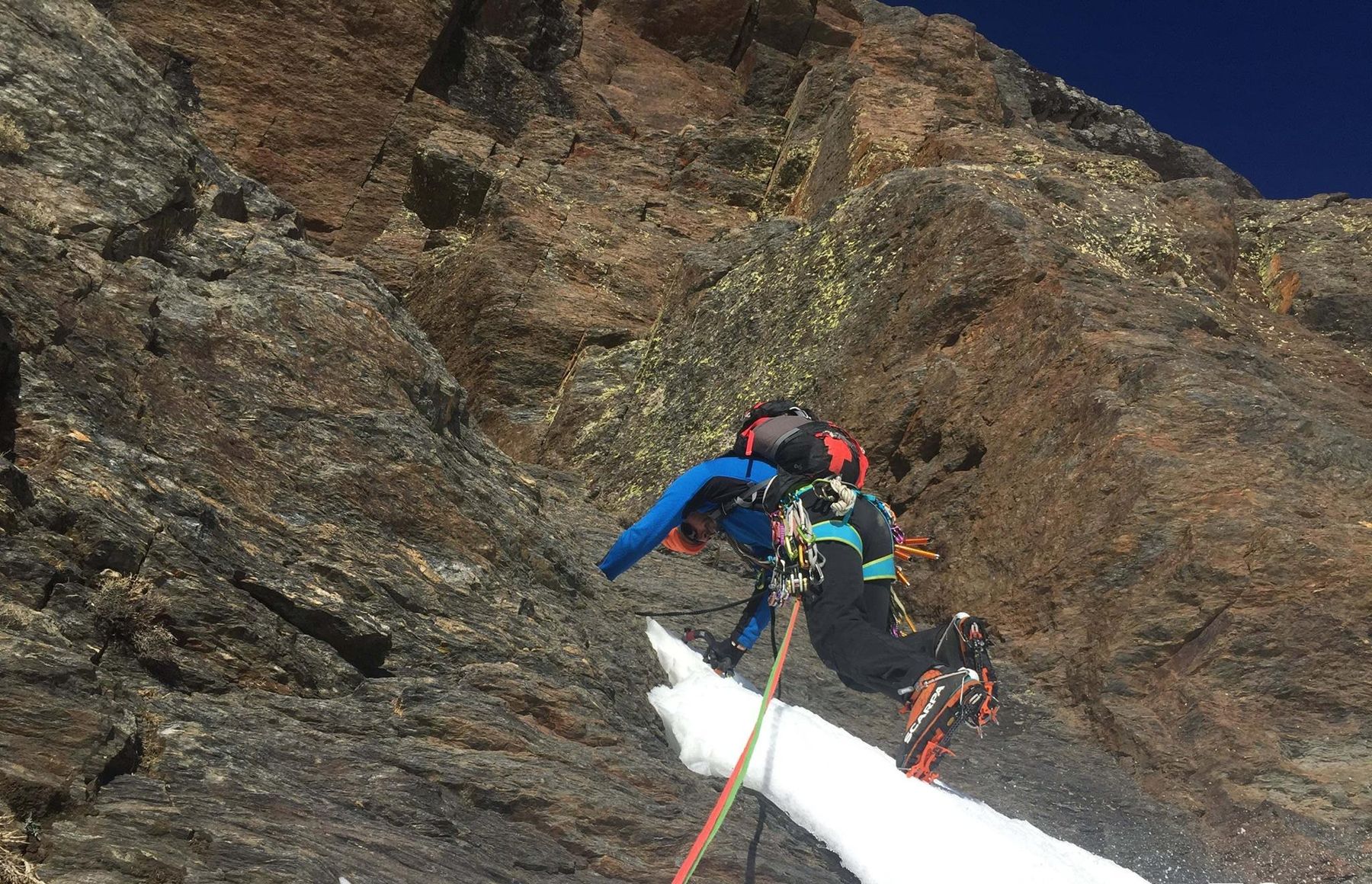 Un alpinista del club escala con crampones un corredor de nieve entre paredes de roca